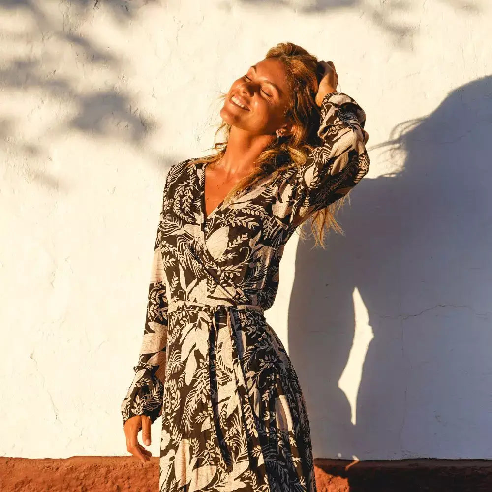 Arena Formentera vestido largo bohemio cruzado en New Saari con estampado botánico en tonos negro y beige, estilo elegante y veraniego para mujer