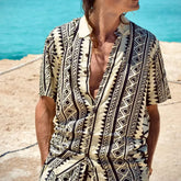 Hombre usando una camisa de rayón estampada en tonos beige y negro frente al mar, ideal para frescura y estilo.