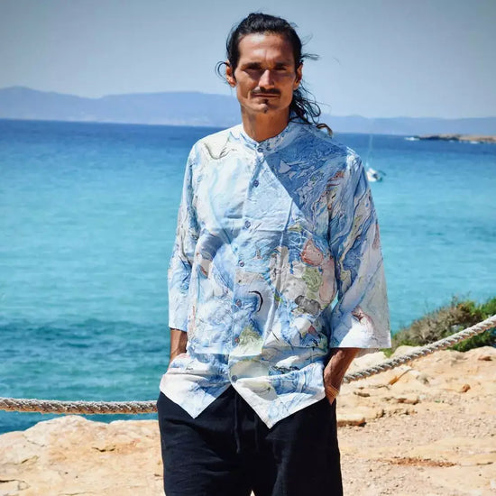 Camisa rayón de hombre Aquarella con estampado azul, en una playa junto al mar.