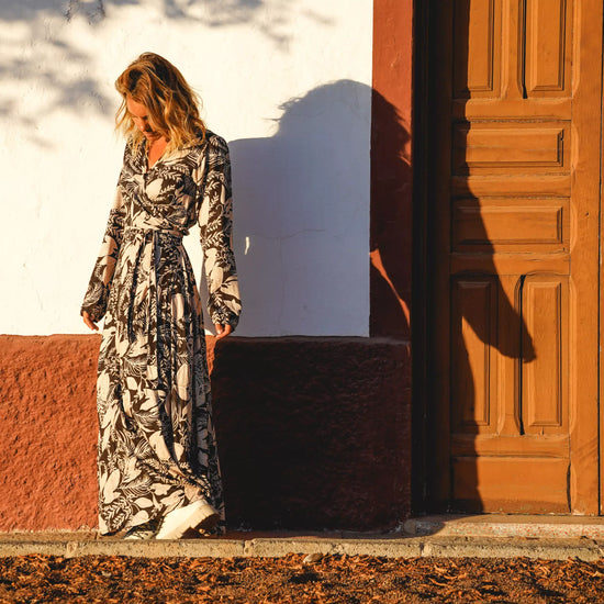 Arena Formentera vestido largo bohemio cruzado en New Saari con estampado botánico en tonos negro y beige, estilo elegante y veraniego para mujer