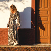 Arena Formentera vestido largo bohemio cruzado en New Saari con estampado botánico en tonos negro y beige, estilo elegante y veraniego para mujer