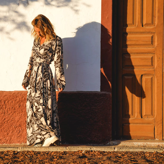 Arena Formentera vestido largo bohemio cruzado en New Saari con estampado botánico en tonos negro y beige, estilo elegante y veraniego para mujer