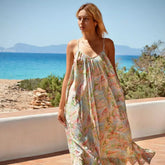Mujer luciendo un vestido bohemio largo Aquarella frente al mar, ideal para días de playa.