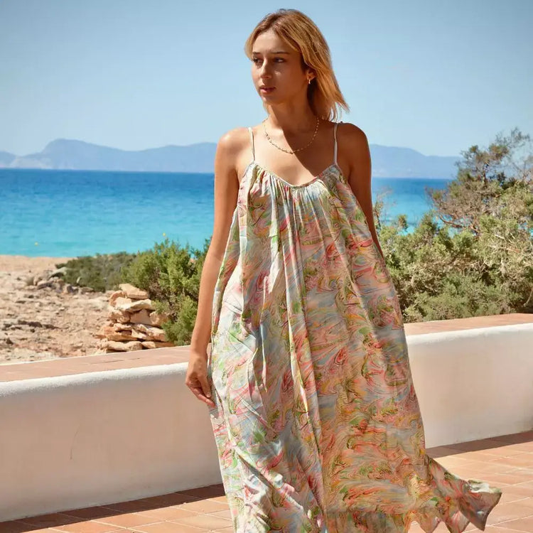 Mujer luciendo un vestido bohemio largo Aquarella frente al mar, ideal para días de playa.