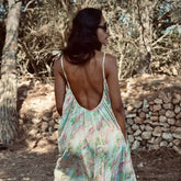 Modelo de espaldas con vestido bohemio largo Aquarella, rodeada de naturaleza y luz suave.